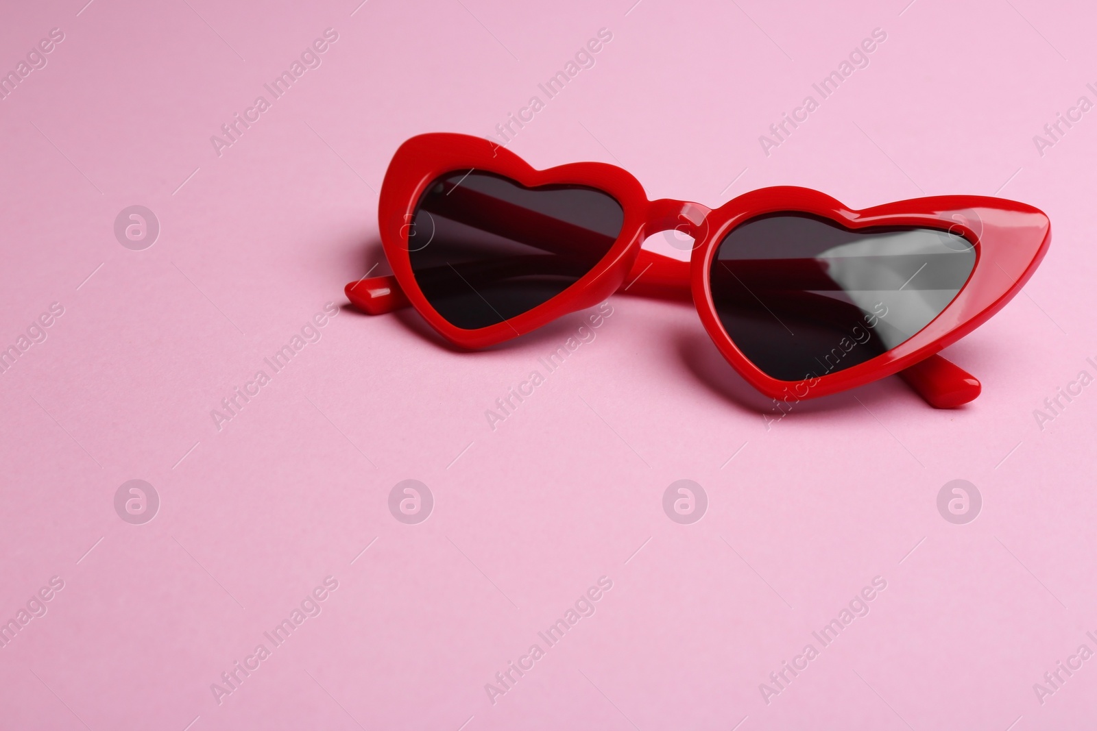 Photo of Stylish heart shaped sunglasses on pink background, space for text. Fashionable accessory