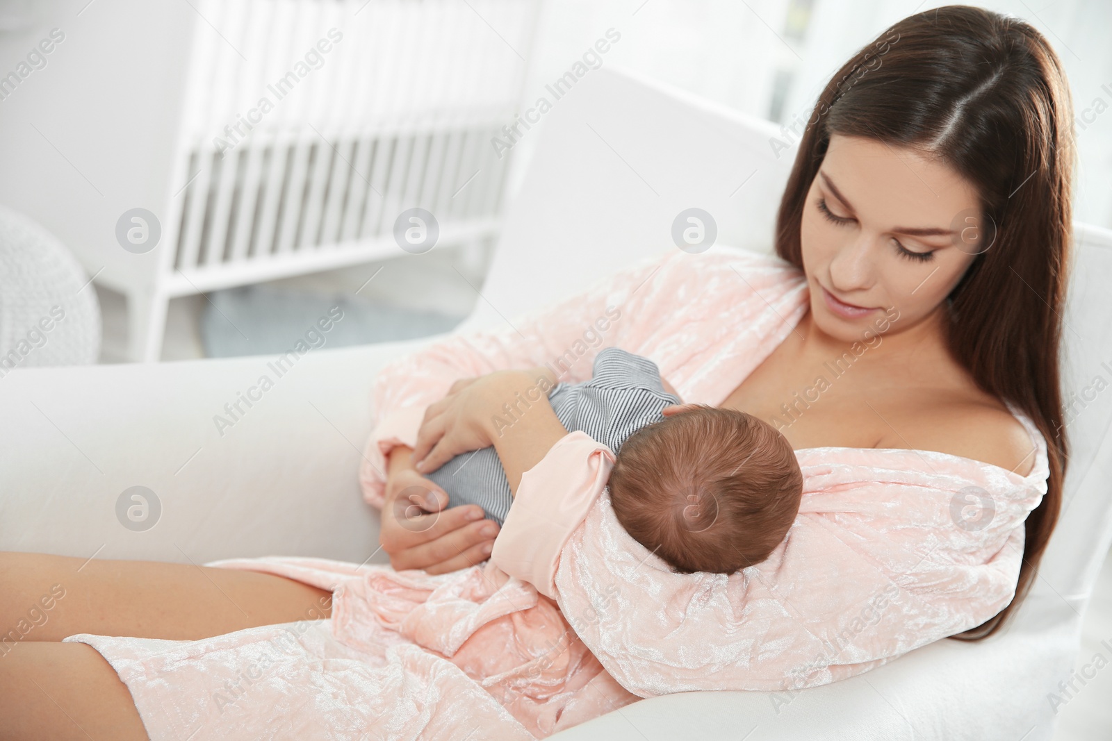 Photo of Young woman breastfeeding her baby in nursery. Space for text