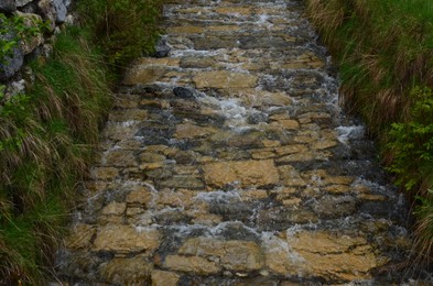 View of beautiful stream flowing on path covered with natural stones