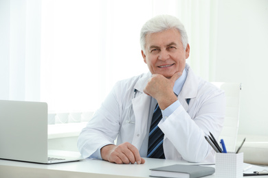 Portrait of senior doctor in white coat at workplace