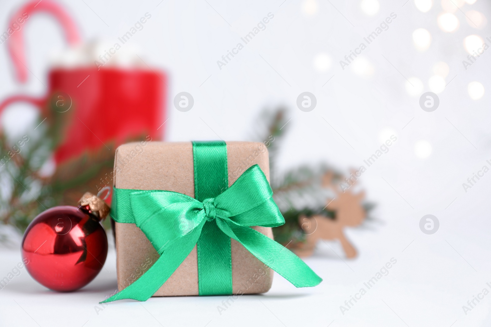Photo of Gift box and Christmas ball on blurred background, closeup. Space for text