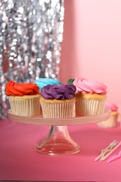 Photo of Delicious cupcakes with bright cream and candles on pink table