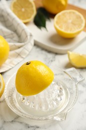 Photo of Glass squeezer and fresh lemons on white marble table