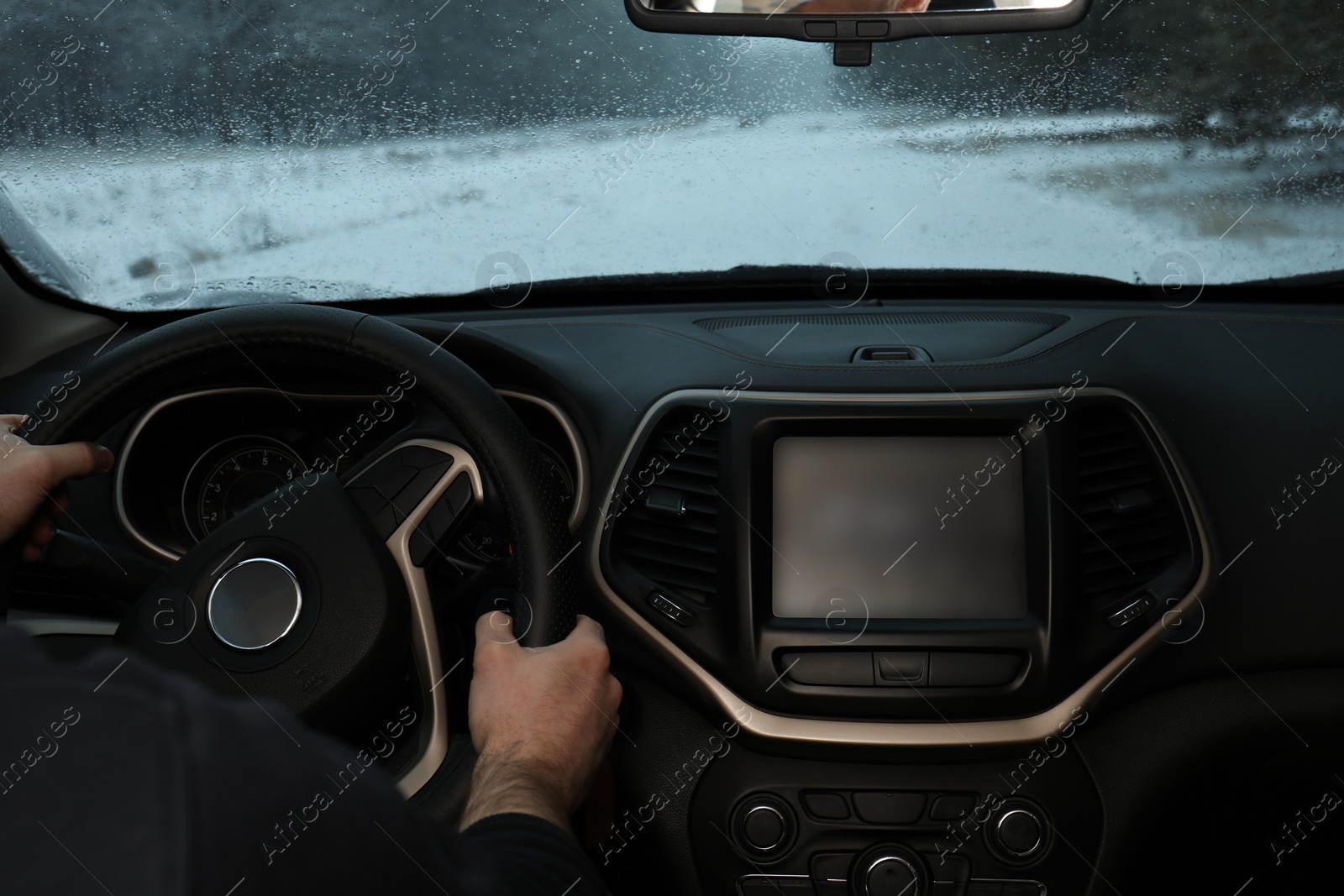 Photo of Young man driving car along winter forest, closeup