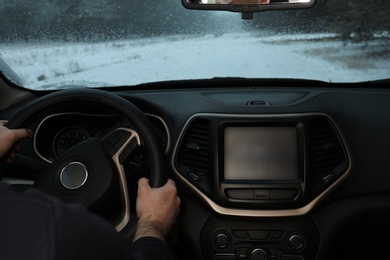 Photo of Young man driving car along winter forest, closeup