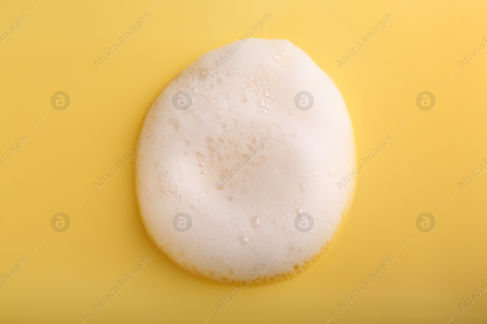 Photo of Sample of fluffy foam on yellow background, top view