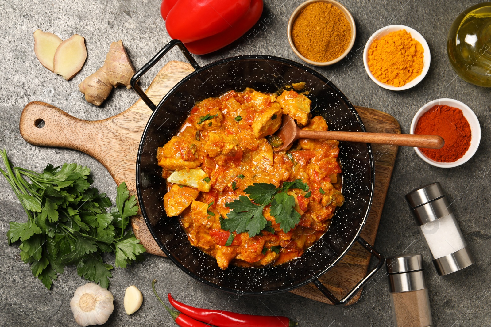 Photo of Delicious chicken curry and ingredients on grey table, flat lay