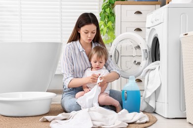 Photo of Mother with her daughter washing baby clothes in bathroom