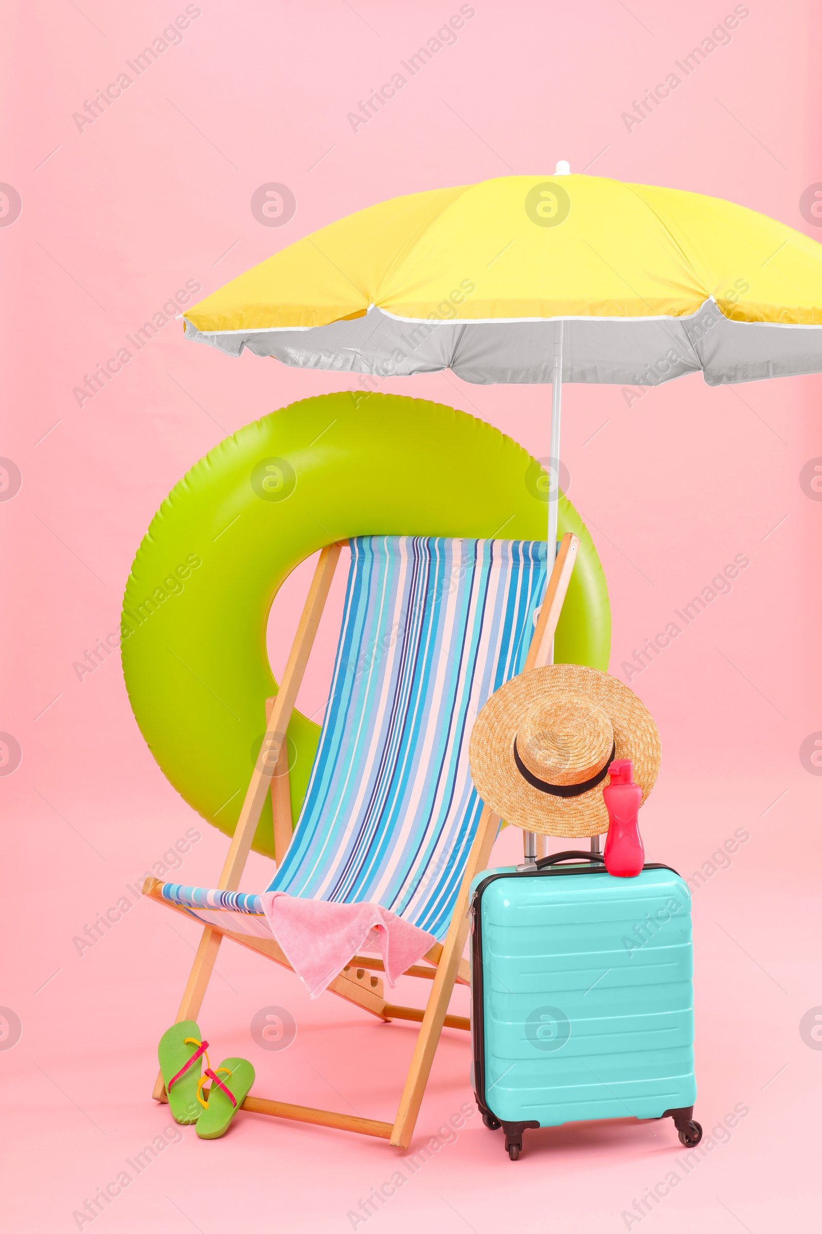 Deck chair, umbrella, suitcase and beach accessories against pink background. Summer vacation Photo of Deck chair, umbrella, suitcase and beach accessories against pink background. Summer vacation