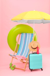 Photo of Deck chair, umbrella, suitcase and beach accessories against pink background. Summer vacation