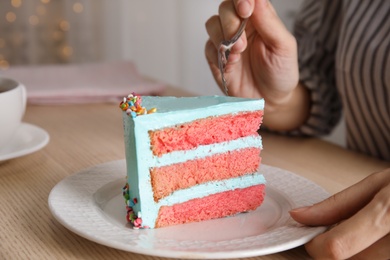 Photo of Woman eating fresh delicious birthday cake at table, closeup