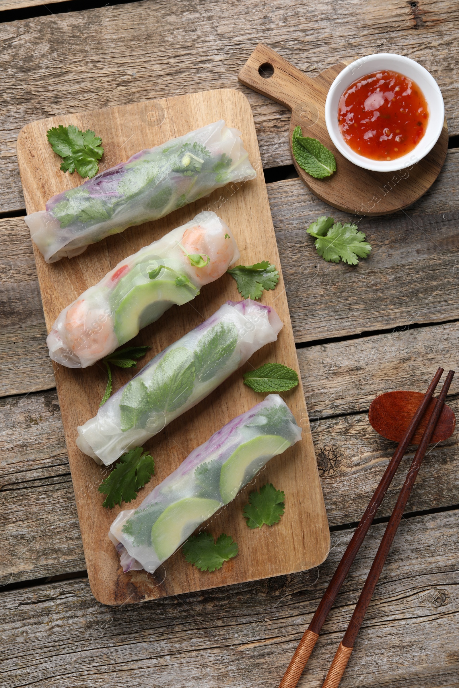 Photo of Delicious spring rolls, sauce and chopsticks on wooden table, top view