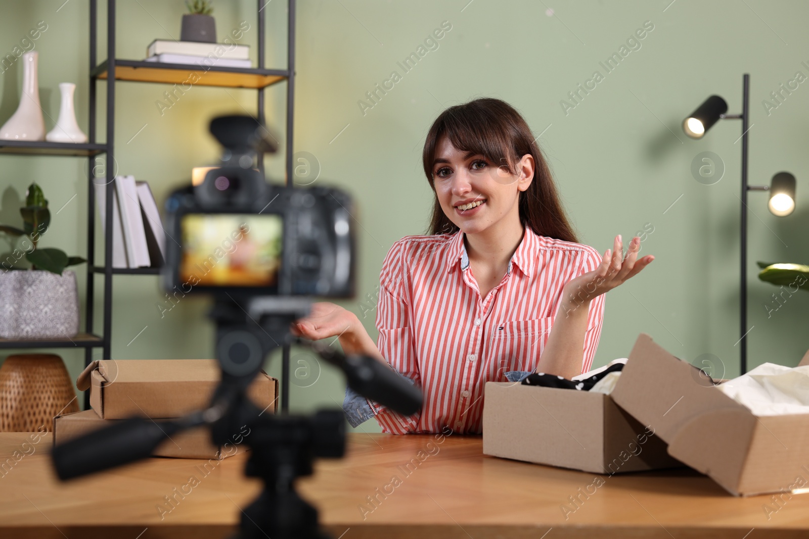 Photo of Smiling fashion blogger recording video while talking about clothes at home