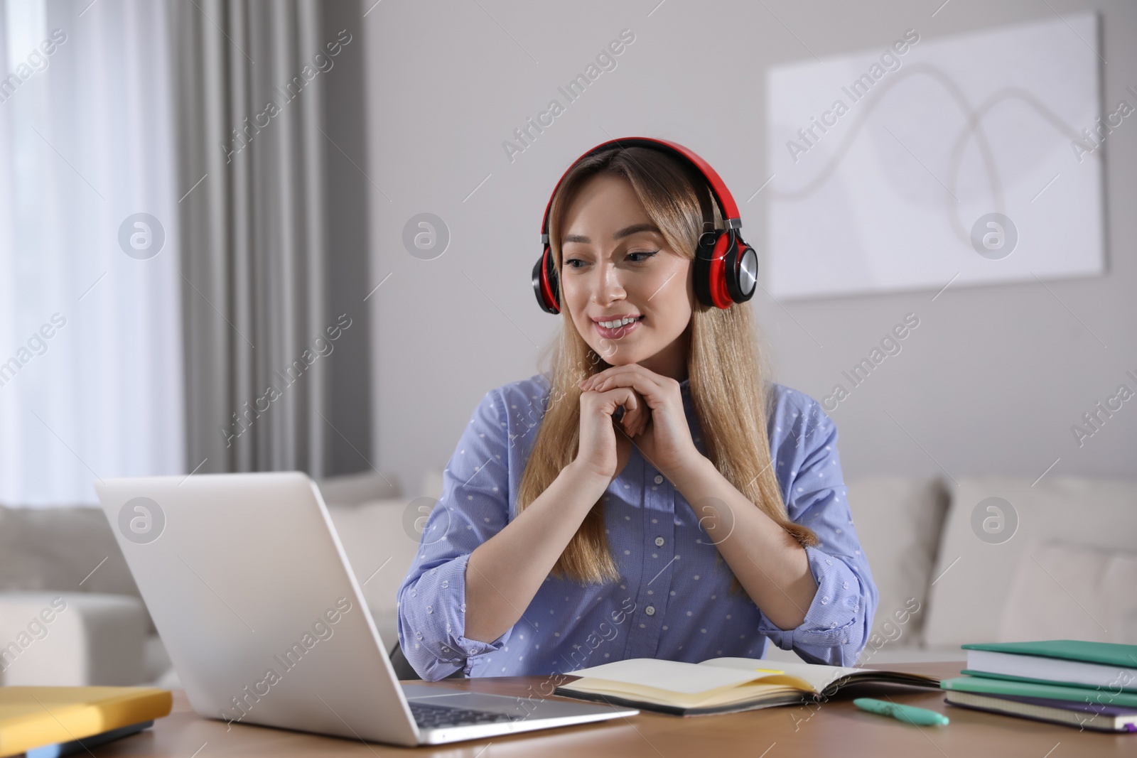 Photo of Young woman watching webinar at table in room