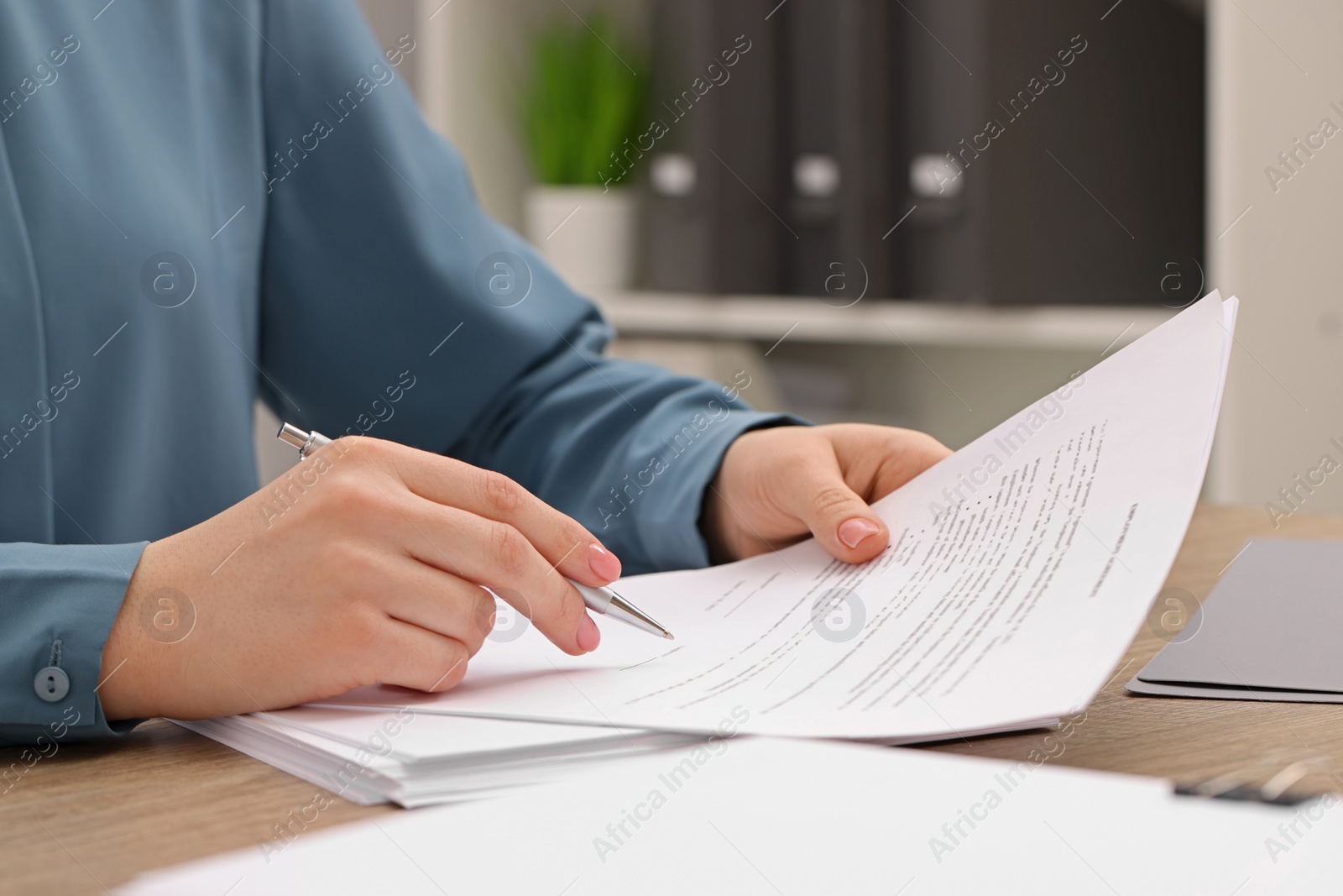 Photo of Woman signing document at wooden table, closeup