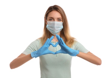 Photo of Young woman in medical gloves and protective mask making heart with hands on white background