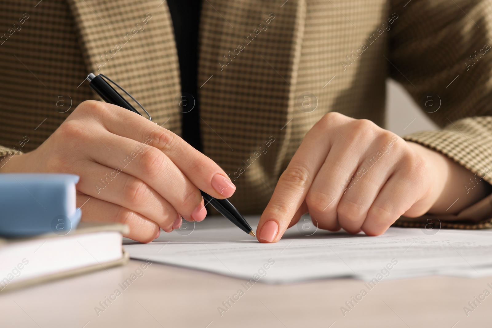 Photo of Woman signing document at table, closeup view