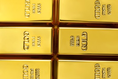 Photo of Many shiny gold bars as background, top view