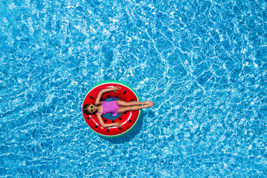 Image of Cute little girl with inflatable ring in swimming pool, top view. Summer vacation