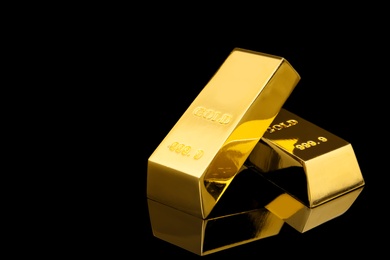 Photo of Shiny gold bars on black background. Space for text