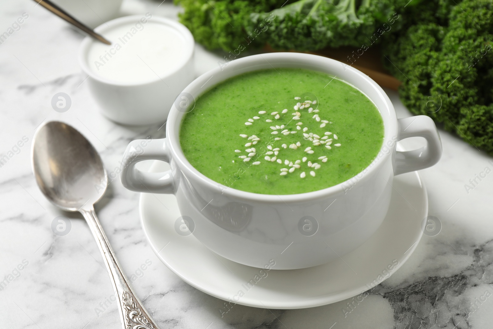 Photo of Tasty kale soup with sesame seeds on white marble table, closeup