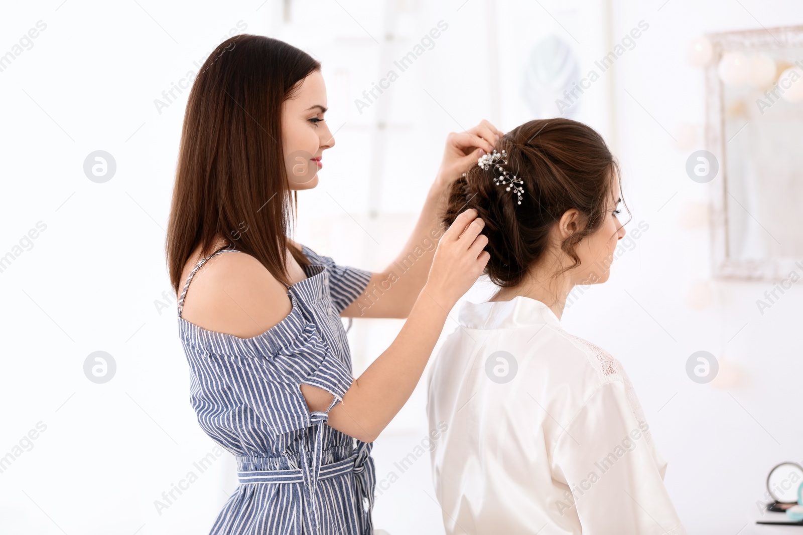 Photo of Professional hairdresser working with young woman in salon