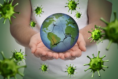 Image of Man holding Earth with medical mask on light background, closeup. Concept of coronavirus outbreak