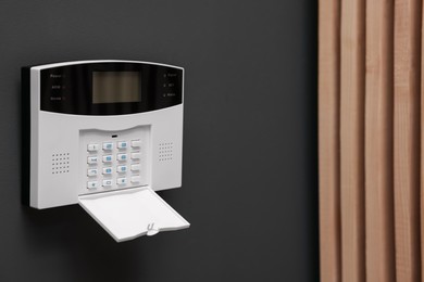 Photo of Home security alarm system on brown wall indoors, space for text