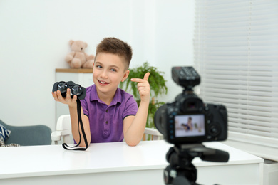 Cute little blogger with binoculars recording video at home