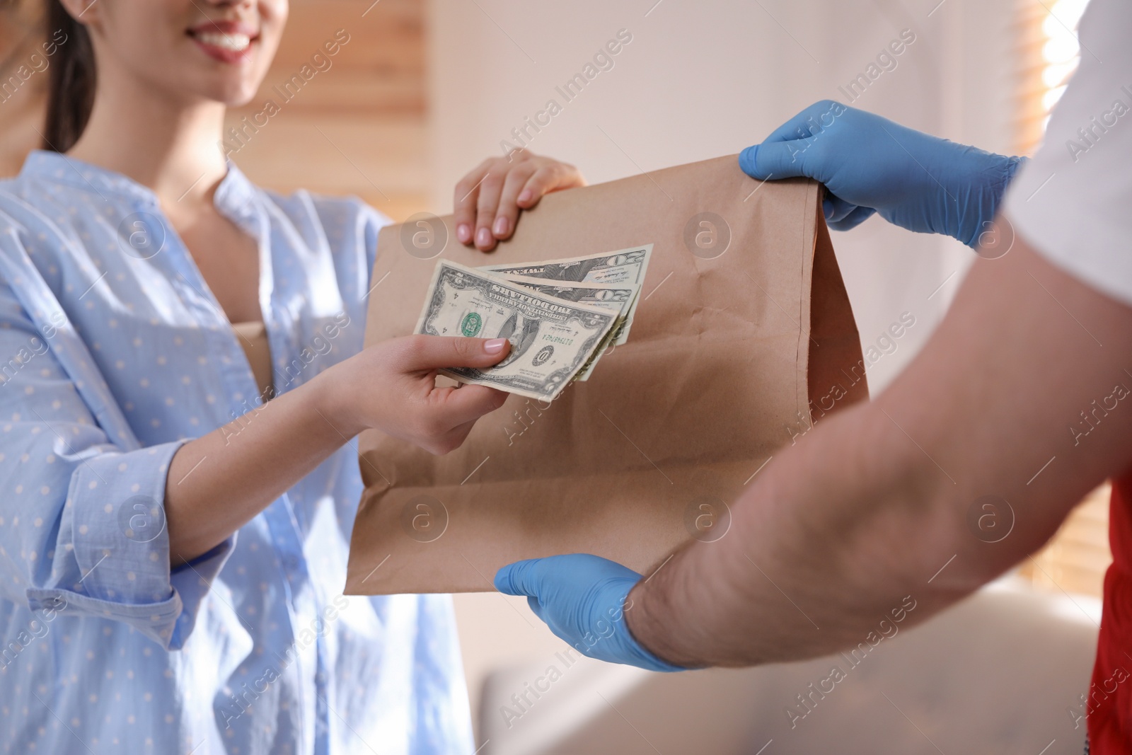 Photo of Woman giving tips to deliveryman indoors, closeup