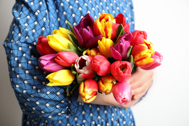Woman holding beautiful spring tulips on white background, closeup