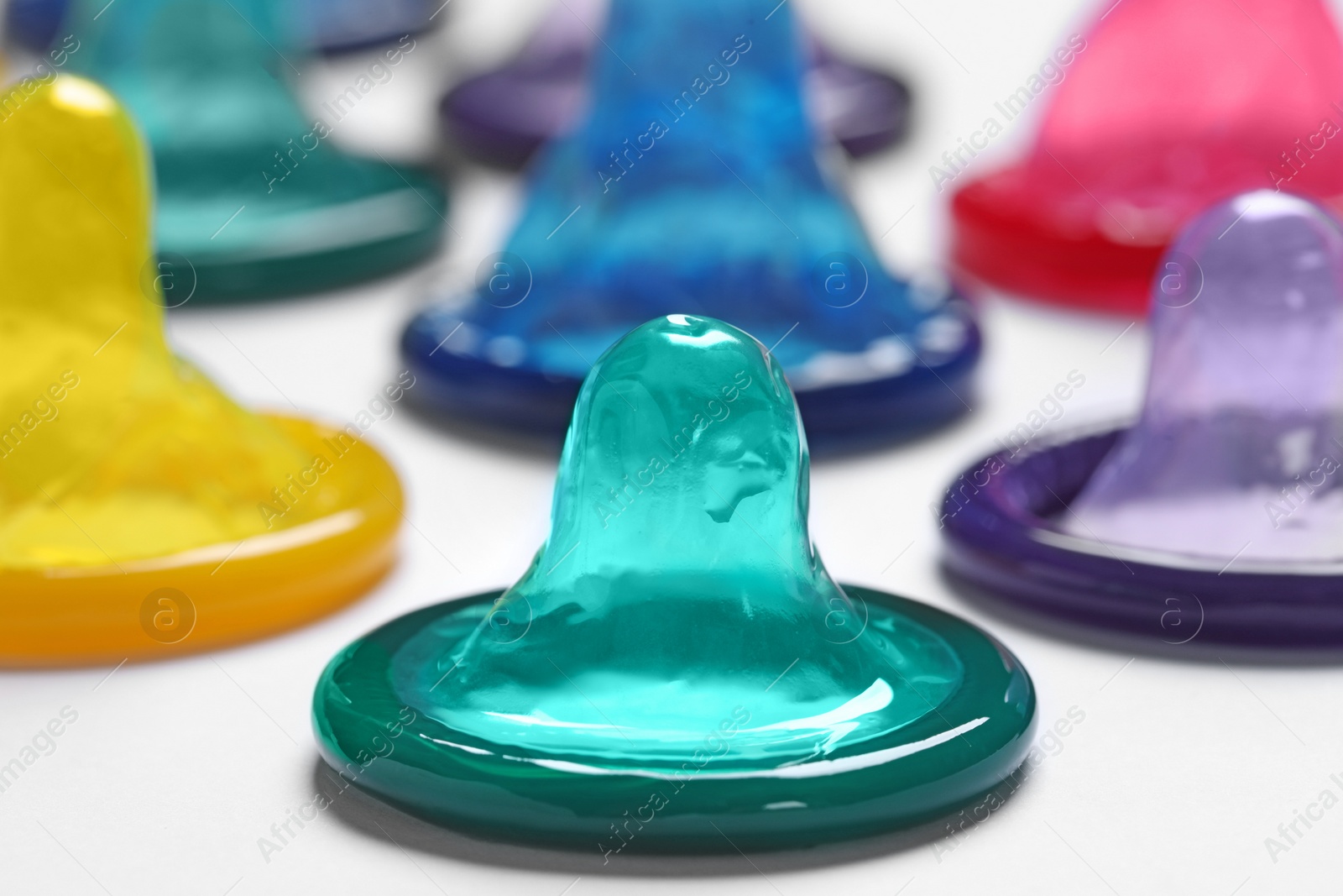 Photo of Colorful condoms on white background, closeup. Safe sex