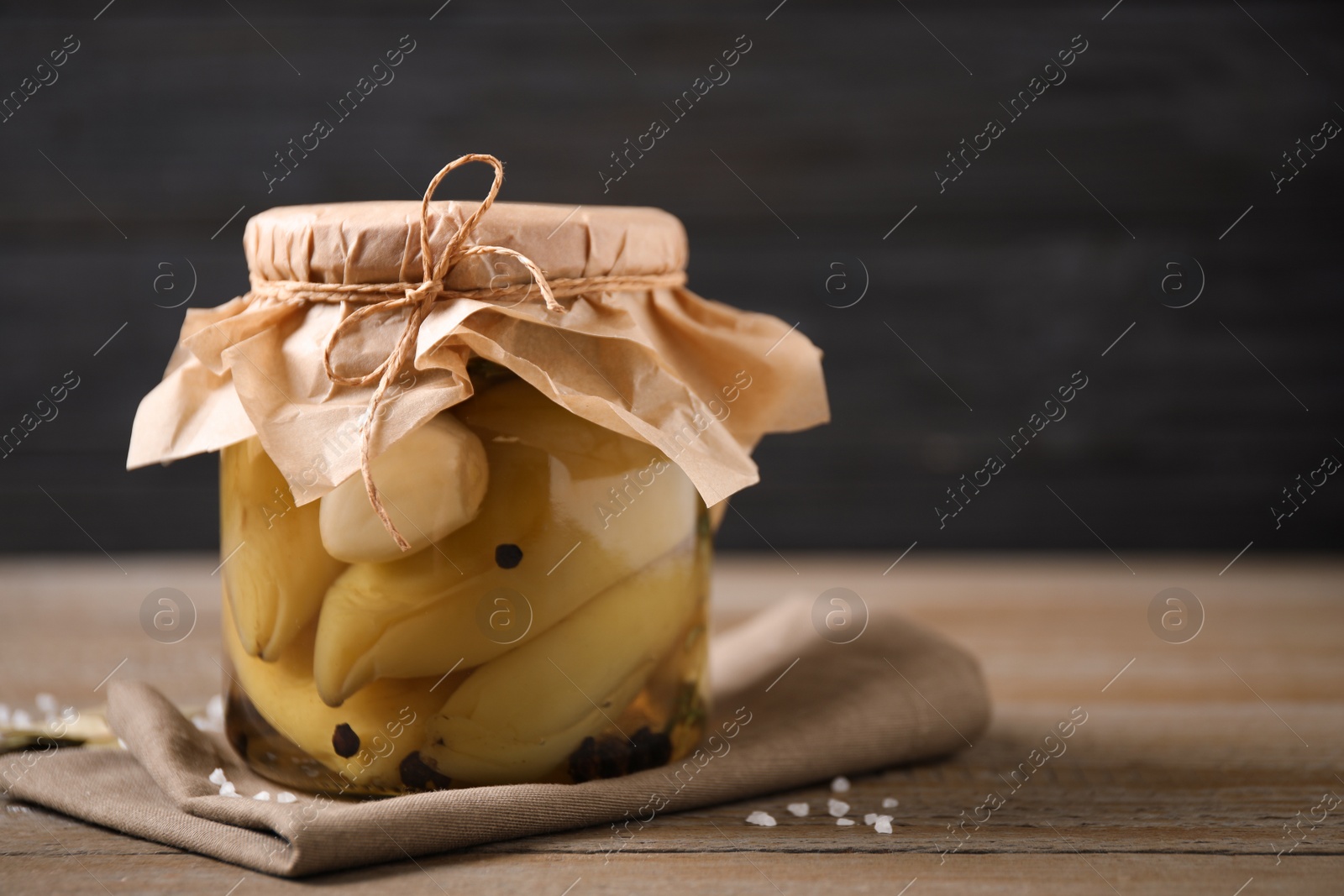 Photo of Glass jar with pickled peppers on wooden table