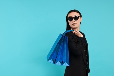 Photo of Beautiful woman with shopping bags on light blue background. Space for text