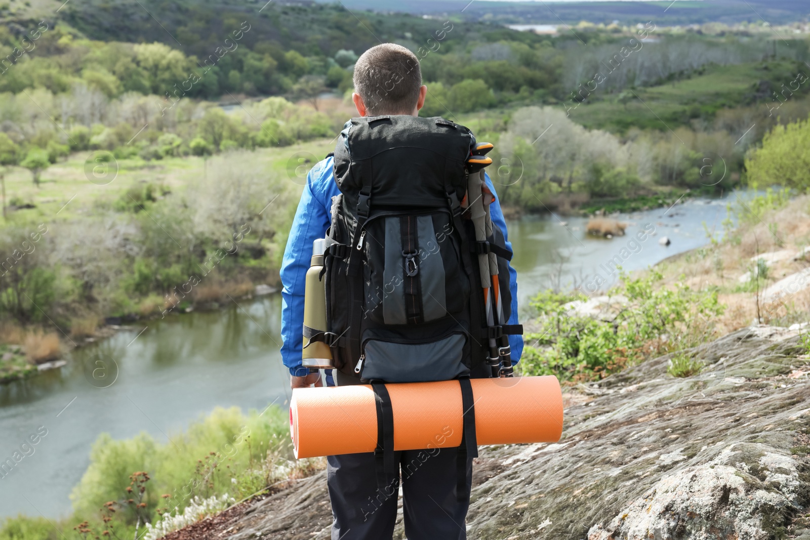 Photo of Hiker with backpack ready for journey on rocky hill near river, back view