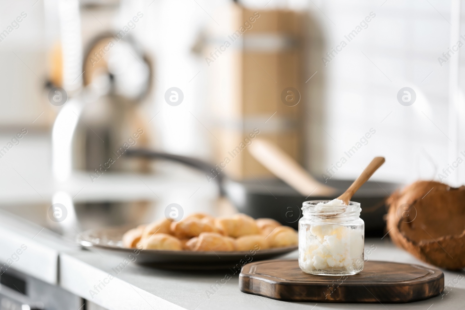 Photo of Jar with coconut oil on table in kitchen. Healthy cooking