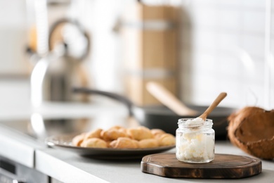 Jar with coconut oil on table in kitchen. Healthy cooking