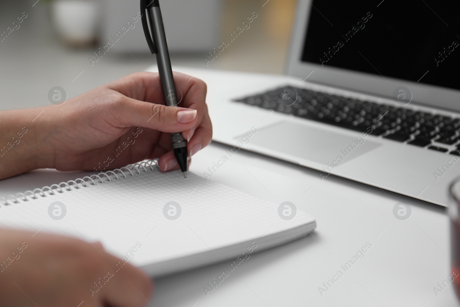 Photo of Left-handed woman writing in notebook at table, closeup