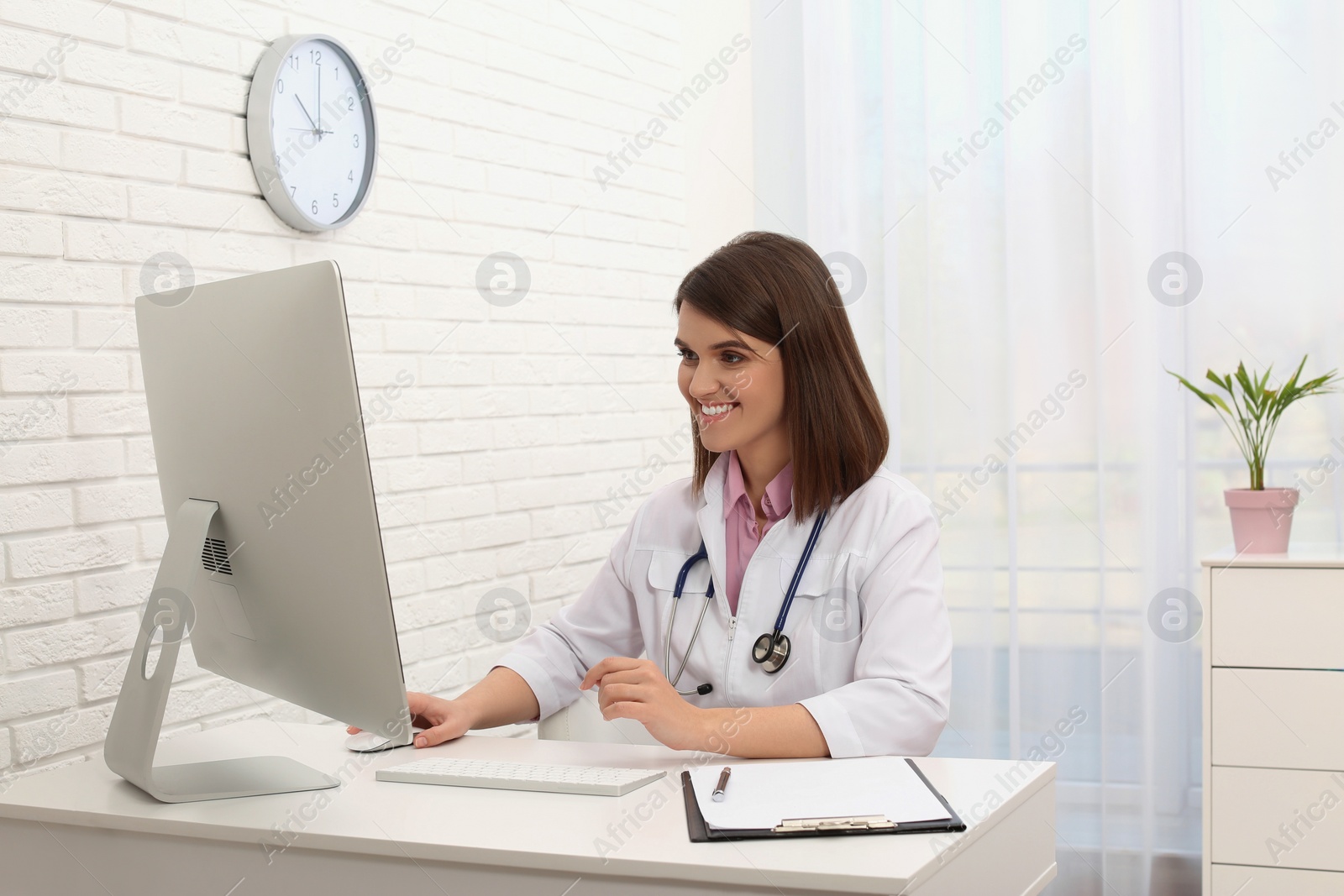 Photo of Pediatrician consulting patient online at table in clinic