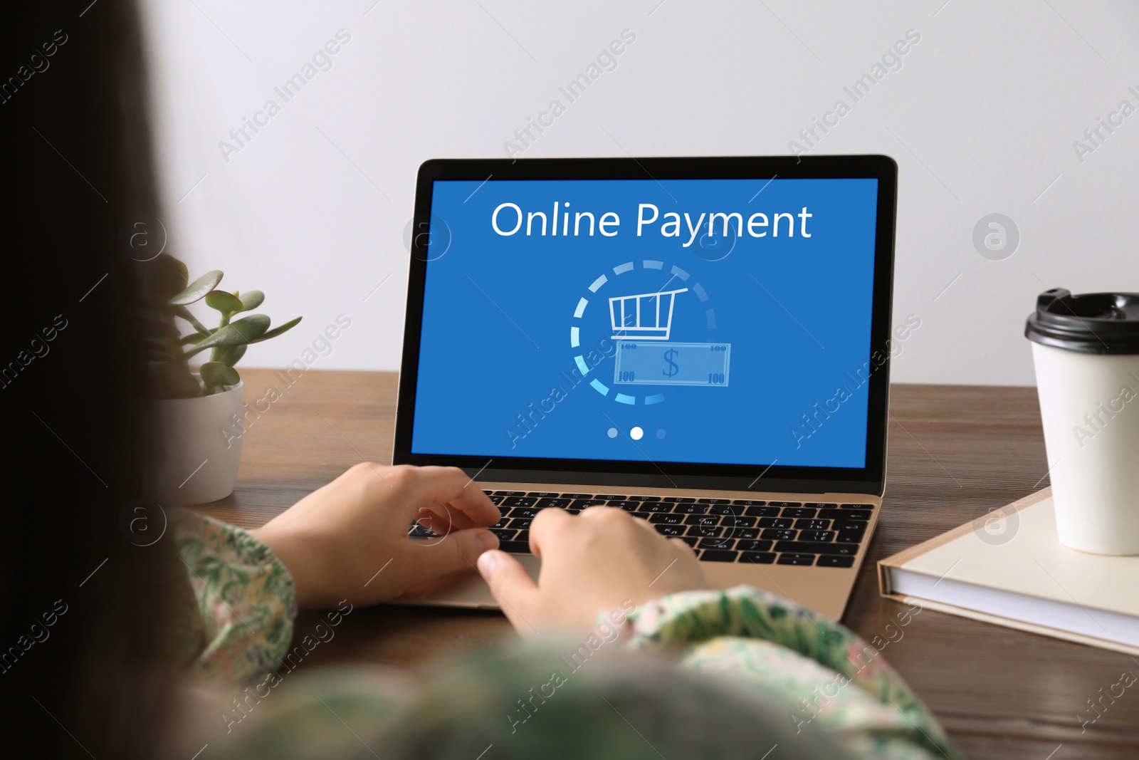 Image of Woman using laptop for online payment at wooden table, closeup