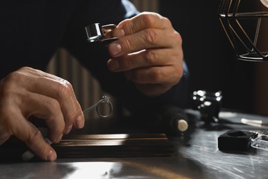 Photo of Professional jeweler working with ring at table, closeup