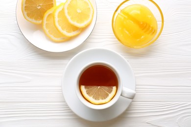Cup with delicious immunity boosting tea, lemon and honey on white wooden table, flat lay