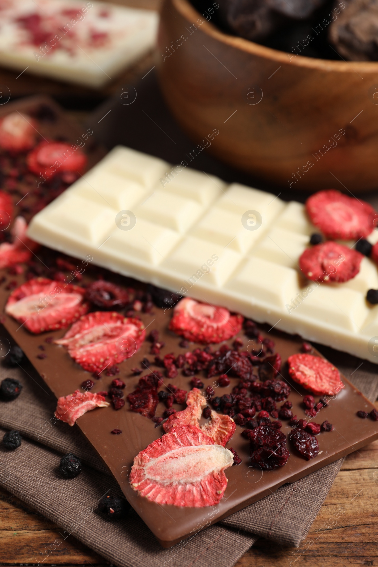 Photo of Different chocolate bars with freeze dried fruits on table, closeup