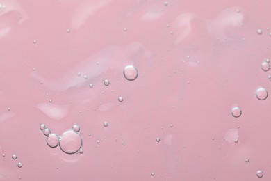 Transparent cleansing gel on pink background, top view. Cosmetic product