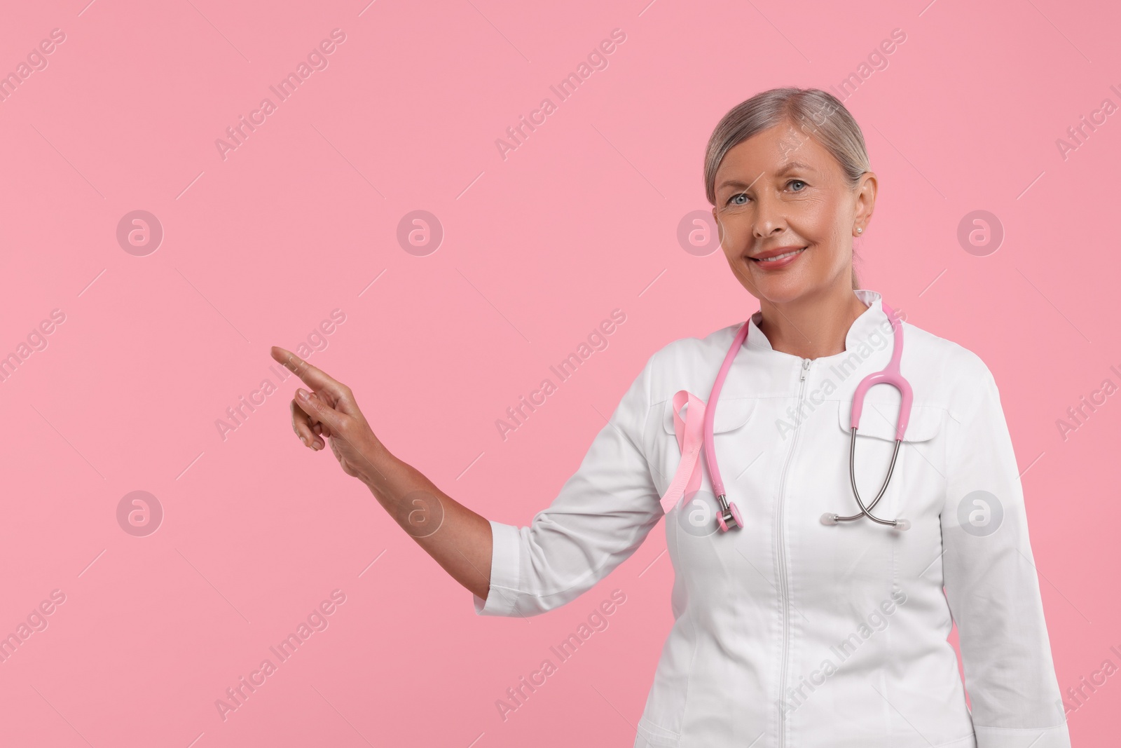 Photo of Doctor with pink ribbon and stethoscope on color background. Breast cancer awareness