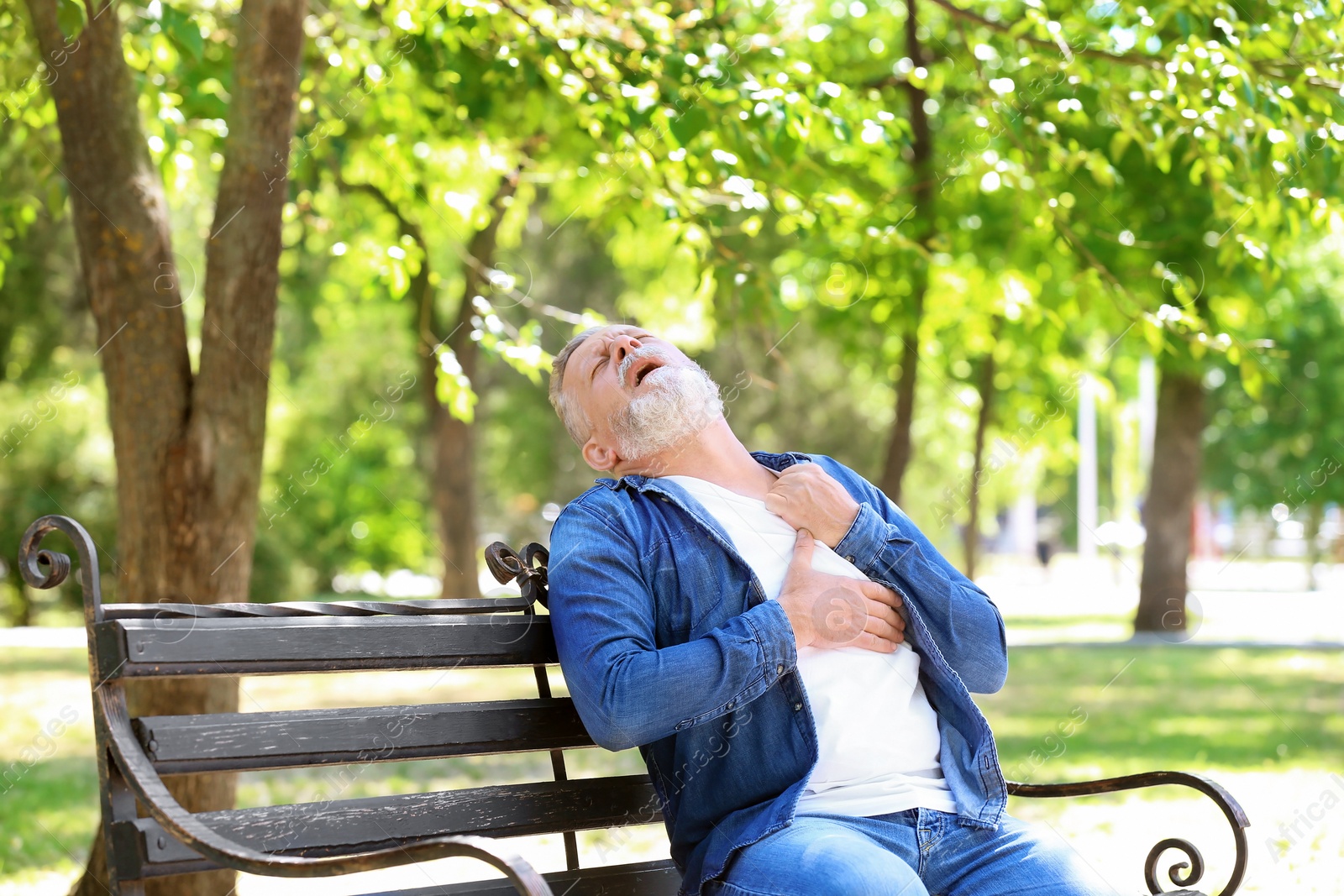 Photo of Mature man having heart attack on bench in park