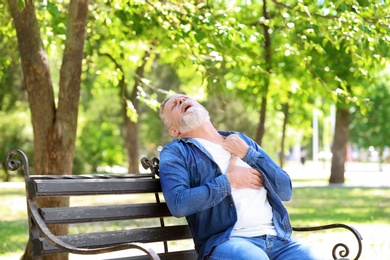 Mature man having heart attack on bench in park