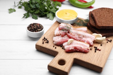 Slices of tasty pork fatback with garlic, rye bread and sauce on white wooden table, closeup