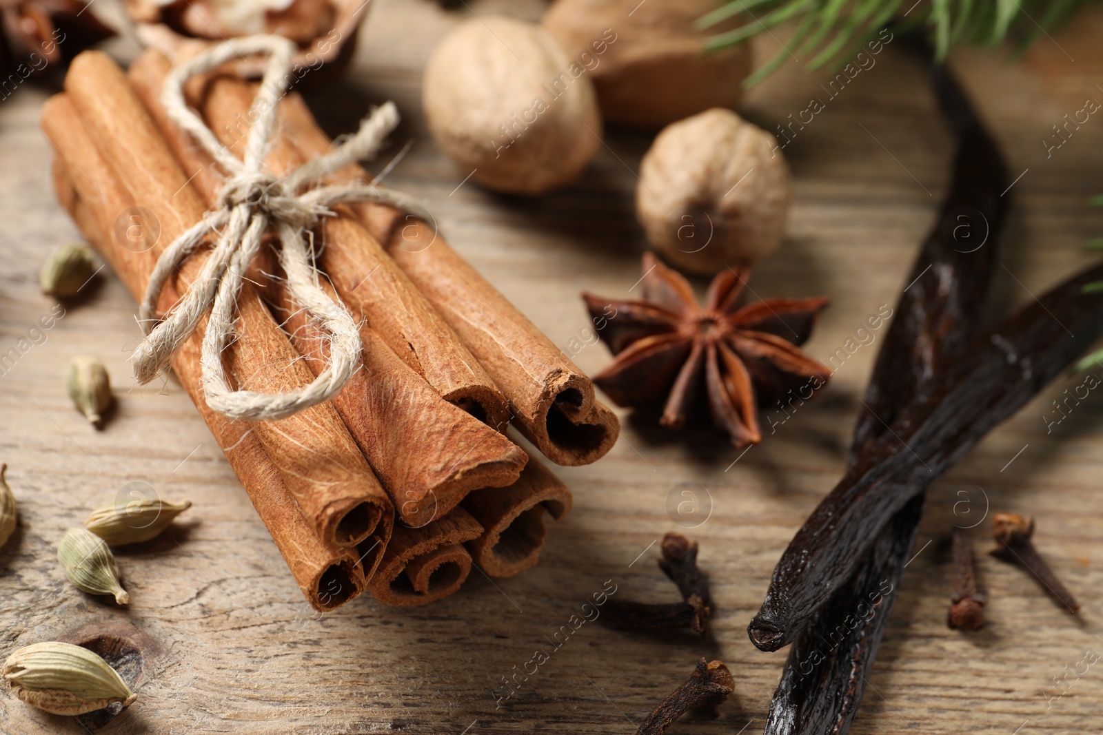 Photo of Cinnamon sticks and other spices on wooden table, closeup