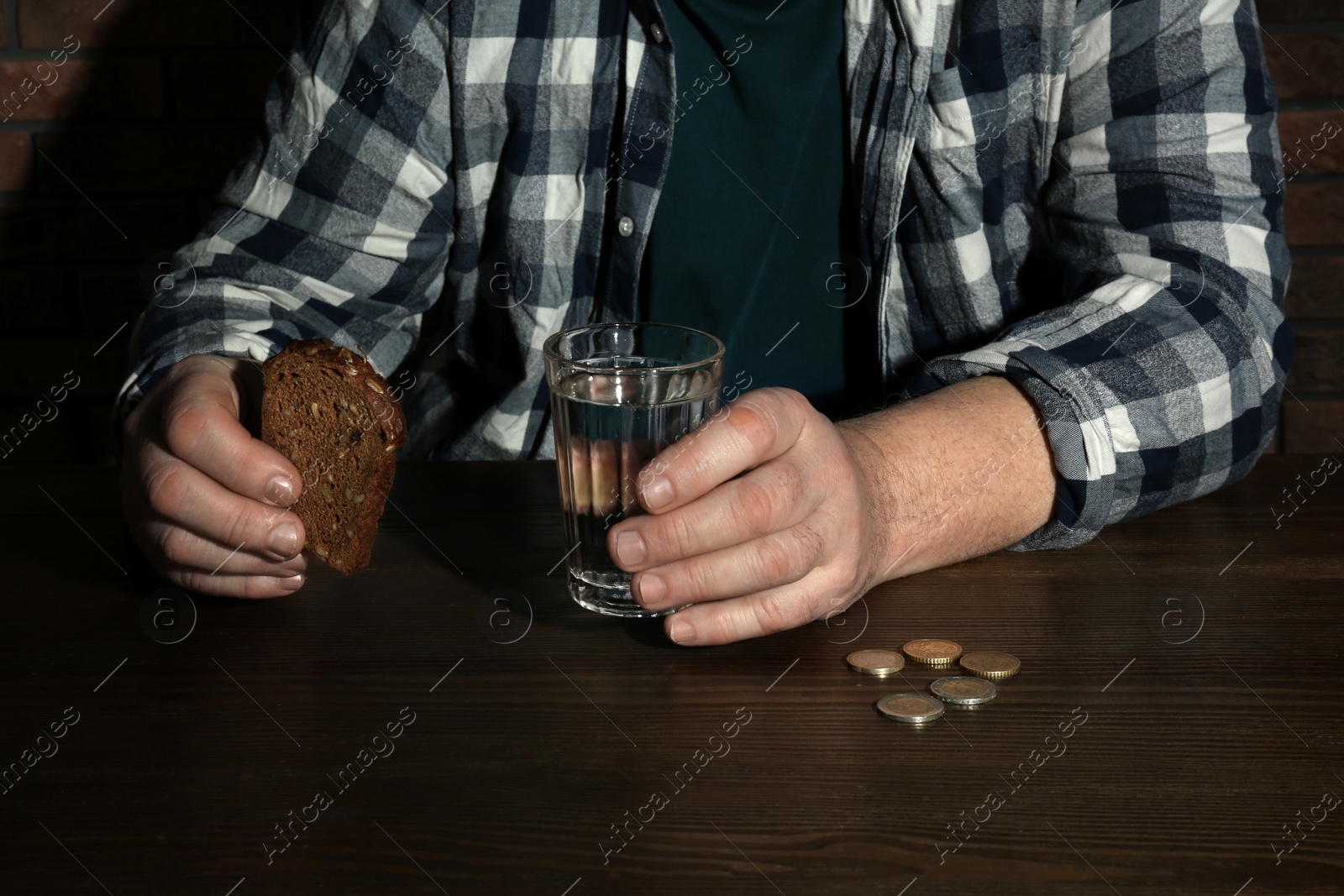 Photo of Poor senior man with bread and glass of water at table, closeup